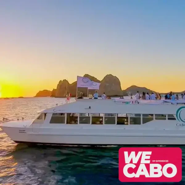 Imagen de un crucero al atardecer en Cabo San Lucas, con vistas al Arco y Playa del Amor, mientras los pasajeros disfrutan de una cena, música en vivo y barra libre.