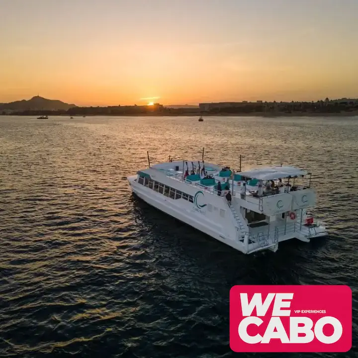 Imagen de un crucero al atardecer en Cabo San Lucas, con vistas al Arco y Playa del Amor, mientras los pasajeros disfrutan de una cena, música en vivo y barra libre.