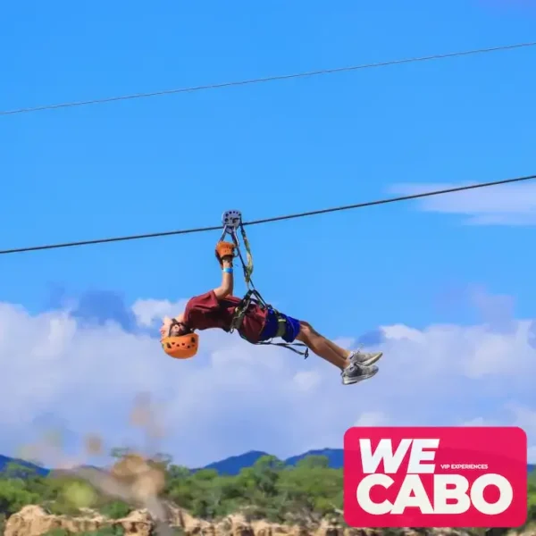 Image of a person gliding on a zipline over a canyon in Los Cabos, surrounded by desert landscape and nature.